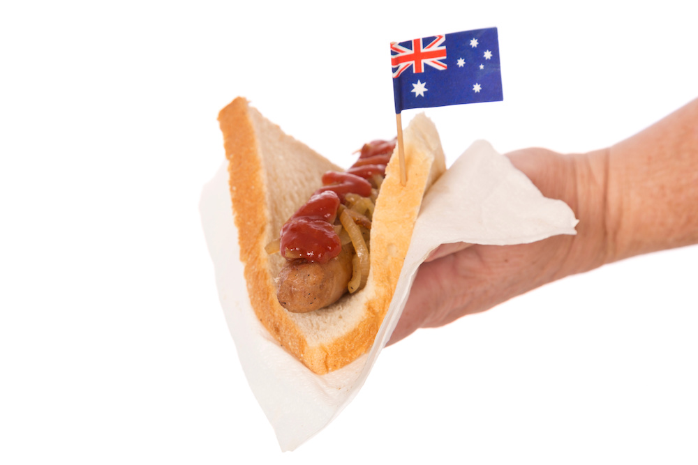Hand holding democracy sausage with Australian flag